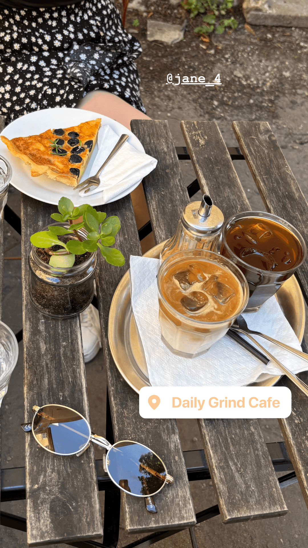 Iced coffees and a slice of quiche on an outdoor patio table at Daily Grind Cafe